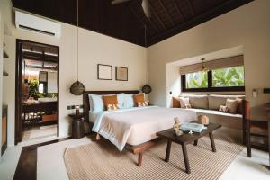 a bedroom with a large bed and a table at ALMA SHANTI Boutique Hotel in Uluwatu
