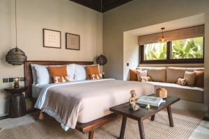 a bedroom with a large bed and a couch at ALMA SHANTI Boutique Hotel in Uluwatu
