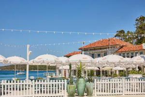 a white fence with umbrellas in front of a building at Manly Beachfront Stays - 3 Bedroom Beachfront with Garden - Walking Distance To Everything in Sydney