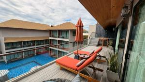 a balcony with an umbrella and chairs and a pool at Ananya Lipe Resort in Ko Lipe