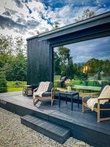a patio with two chairs and a table and a window at Forest Chalet in Porumbacu de Sus