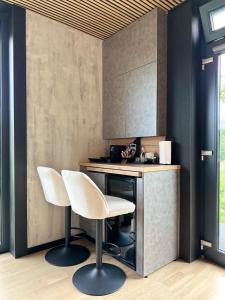 a kitchen with two white chairs and a counter at Forest Chalet in Porumbacu de Sus