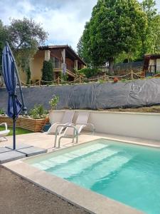 a swimming pool with two chairs and an umbrella at Gite de la Mouline in Lectoure