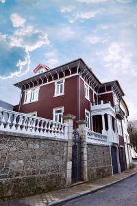 una casa roja y blanca con una valla de piedra en Casa com Historia, en Covilhã