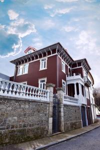 a red and white house with a stone fence at Casa com Historia in Covilhã