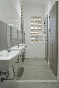 a white bathroom with three sinks and a mirror at New Hostel Braga in Bandung