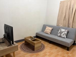 a living room with a couch and a tv at Mama's Tree Homey Studio in Ban Klaeng Lang
