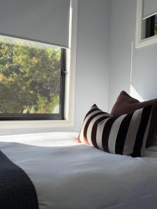 a bed with black and white pillows and a window at Lusso - Boutique Accommodation in Whitfield