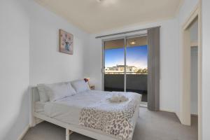 a white bedroom with a bed and a window at Modern Metro by Host Solutions in Mawson Lakes