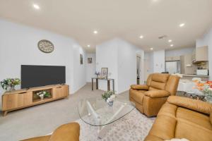 a living room with a tv and a couch and chairs at Modern Metro by Host Solutions in Mawson Lakes