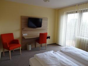 ヴェルトハイムにあるGasthof Hotel Zum Rossのベッド1台、椅子2脚、テレビが備わる客室です。