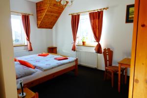 a bedroom with a bed and a table and windows at Penzion U Studánky in Karlovy Vary