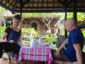 a man and a woman sitting at a table with a dog at Wina Ubud B&B in Ubud