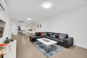 a living room with a black couch and a table at Sub-Penthouse with Marina View by Host Solutions in Glenelg