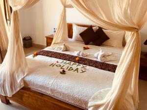 a bedroom with a bed with happy holidays written on it at Dika Homestay in Sidemen