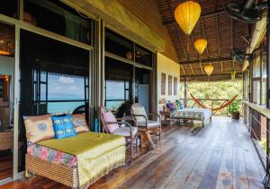 a screened in porch with a couch and chairs at Villa Anahata in Ban Tai