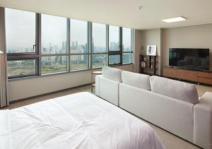 a bedroom with a large white bed and a flat screen tv at Incheon Songdo Stay31 in Incheon