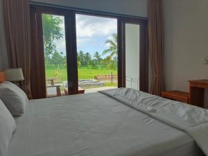 a bedroom with a large bed with a large window at Nêst Guesthouse Tetebatu in Tetebatu