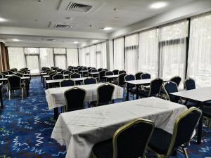 a conference room with tables and chairs and windows at Central Park Hotel 中央公园酒店 in Jalal-Abad