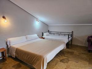 two beds in a room with white sheets at Hostal Restaurante Las Cavenes Del Cabaco in El Cabaco