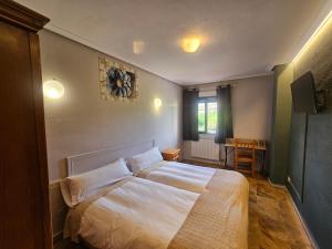 a bedroom with a large bed with white sheets at Hostal Restaurante Las Cavenes Del Cabaco in El Cabaco