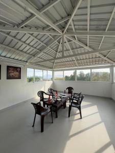 a dining room with a table and chairs and windows at Yercaud Rathna Residency in Yercaud