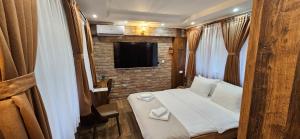 a small room with a bed and a tv at Hotel Babino Brdo in Derventa