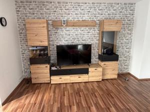 a living room with a tv and a brick wall at Ferienwohnung Alina in Hilders