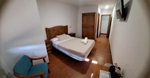 a small bedroom with a bed and a blue chair at Hostal Restaurante Monterde de Albarracín in Monterde de Albarracín