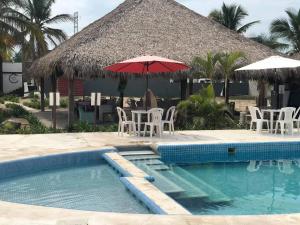a pool with an umbrella and chairs and a table with at Pacha beach club in Barra de Tuxpan