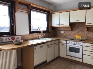 a kitchen with white cabinets and a sink at Vina am Ring Apartment in Mannebach