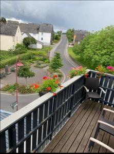 a balcony with a view of a road and flowers at Vina am Ring Apartment in Mannebach