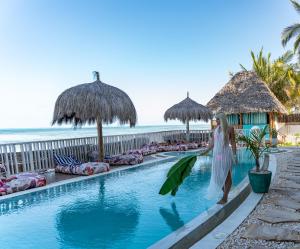 a woman in a white dress standing next to a swimming pool at ZAN Jambiani Beach House in Jambiani +24 photos
