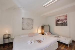 a white bedroom with two beds and a mirror at Maroggia Apartments in Maroggia