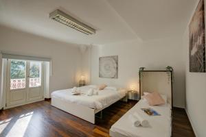 a white bedroom with two beds and a window at Maroggia Apartments in Maroggia