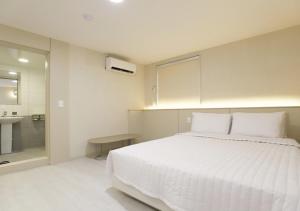ein Schlafzimmer mit einem weißen Bett und einem Waschbecken in der Unterkunft Chuncheon Pine Tree Hotel in Chuncheon