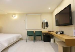 ein Hotelzimmer mit einem Bett und einem Schreibtisch mit zwei Stühlen in der Unterkunft Chuncheon Pine Tree Hotel in Chuncheon