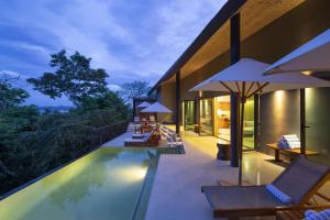 a pool with chairs and umbrellas next to a building at Andaz Peninsula Papagayo Resort, Costa Rica, by Hyatt in Culebra
