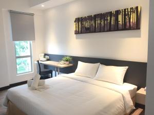 a bedroom with a large white bed and a desk at Fuller Hotel Kulim in Kulim