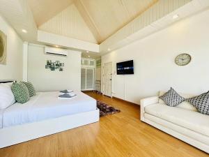 a bedroom with a white bed and a couch at Villa H in Surin Beach