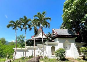 a white building with palm trees in front of it at Villa H in Surin Beach
