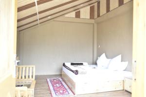 a bedroom with a white bed and a wooden ceiling at Casa De Barro in Jagatsukh