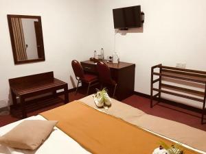 a room with two beds and a desk and a mirror at Marigoldhome hotel and restaurant in Nuwara Eliya