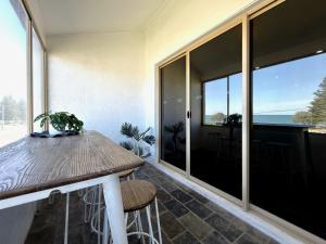 a dining room with a table and a view of the ocean at Sound Views Apartment in Safety Bay