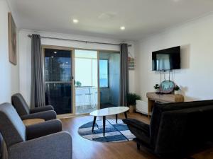 a living room with a couch and chairs and a tv at Sound Views Apartment in Safety Bay