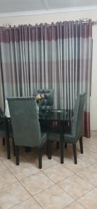a dining room with a table and chairs and curtains at Tinotenda Cottage in Harare +18 photos