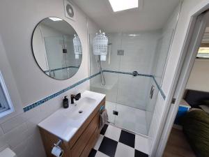 a bathroom with a sink and a shower with a mirror at Beach Pad in Whangamata +11 photos