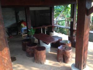 a wooden bench and stools sitting under a porch at Monkeaw in Mae On