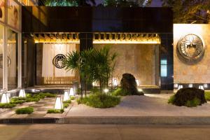 a building with a courtyard with plants in front of it at Bandara Suites Silom, Bangkok in Bangkok
