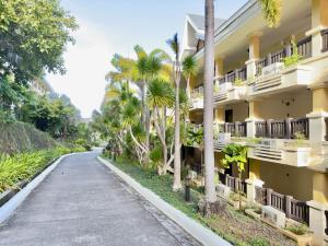 an empty street in front of a building with palm trees at Alta Vista Residences H102 in Boracay